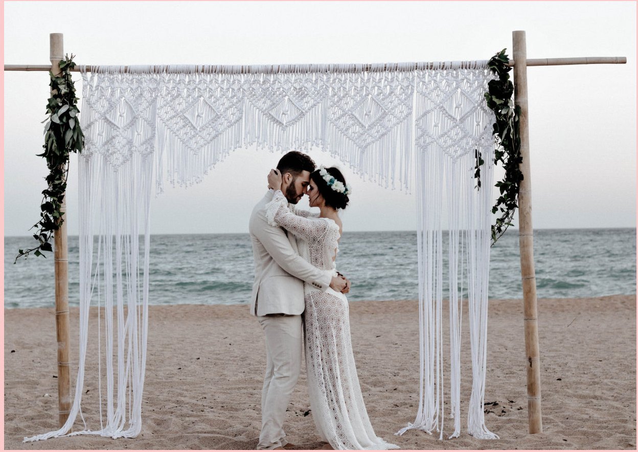 A ceremony arch on the sand, with open water behind it