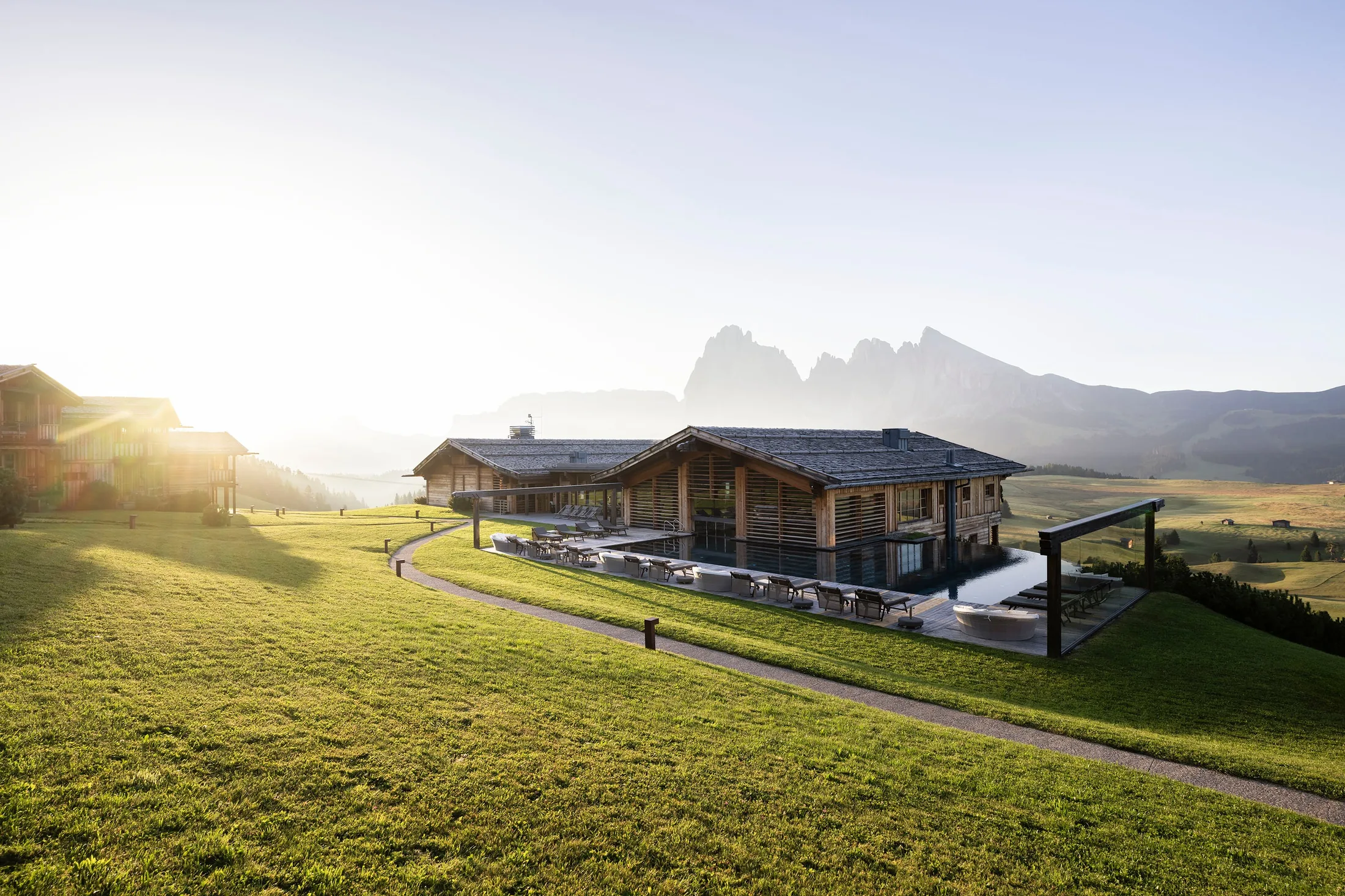 ADLER Lodge ALPE on Alpe di Siusi: the wooden lodge, pool terrace and chalets on the Seiser Alm plateau