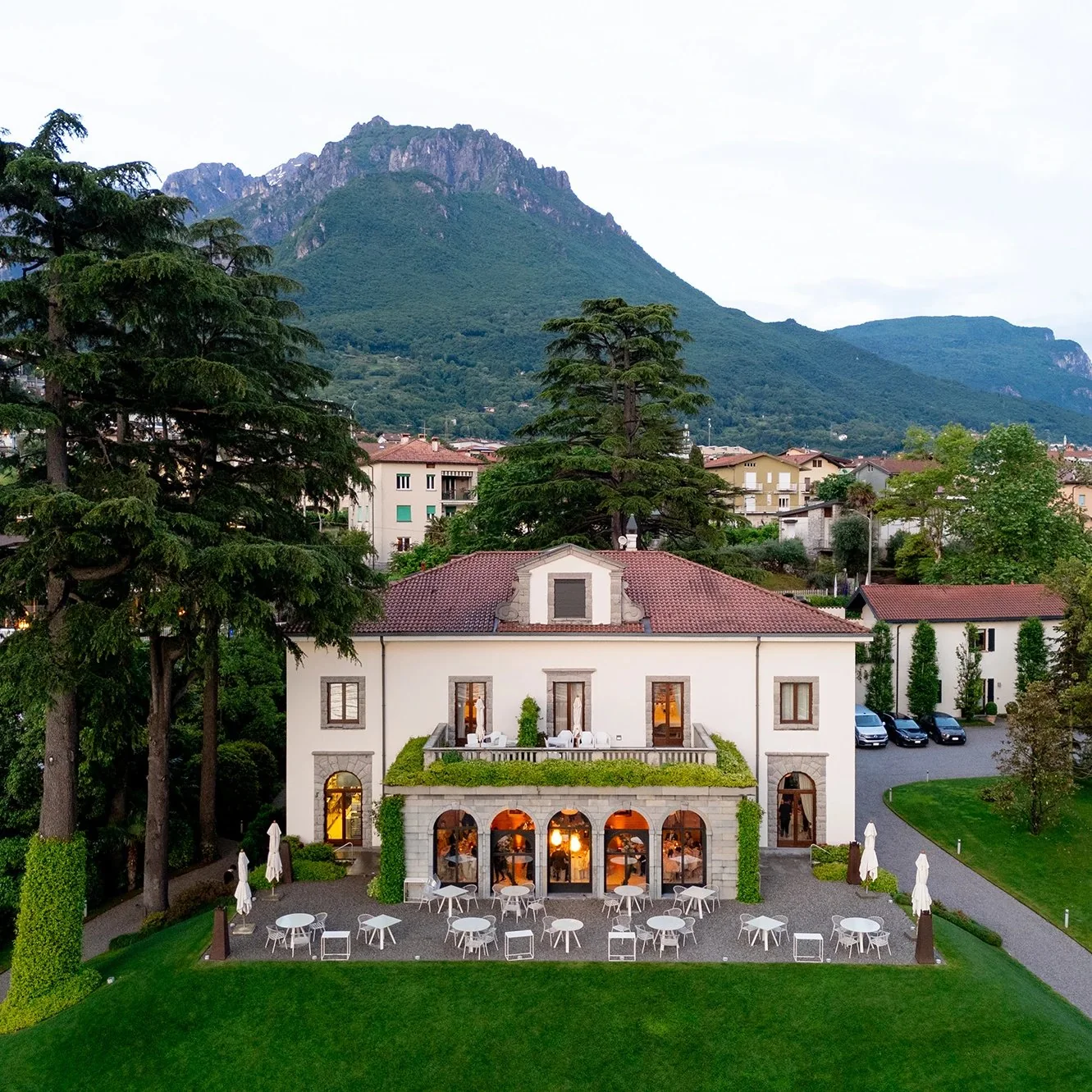 Villa Lario Resort in Mandello del Lario: the villa façade, terrace and lawn at dusk, with the mountain behind