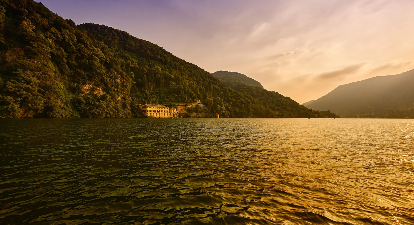 Villa Pliniana in Torno, the palazzo at the water’s edge beneath the wooded cliff, photographed from Lake Como