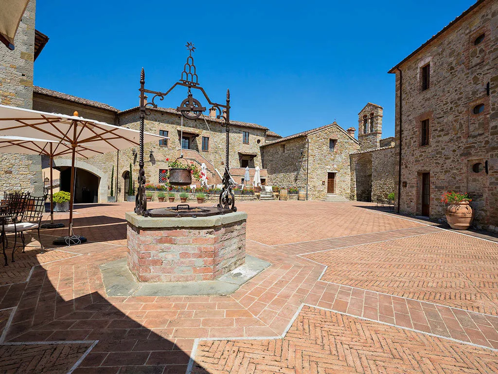 Castel Monastero: the brick piazza and stone well in the Chianti hamlet