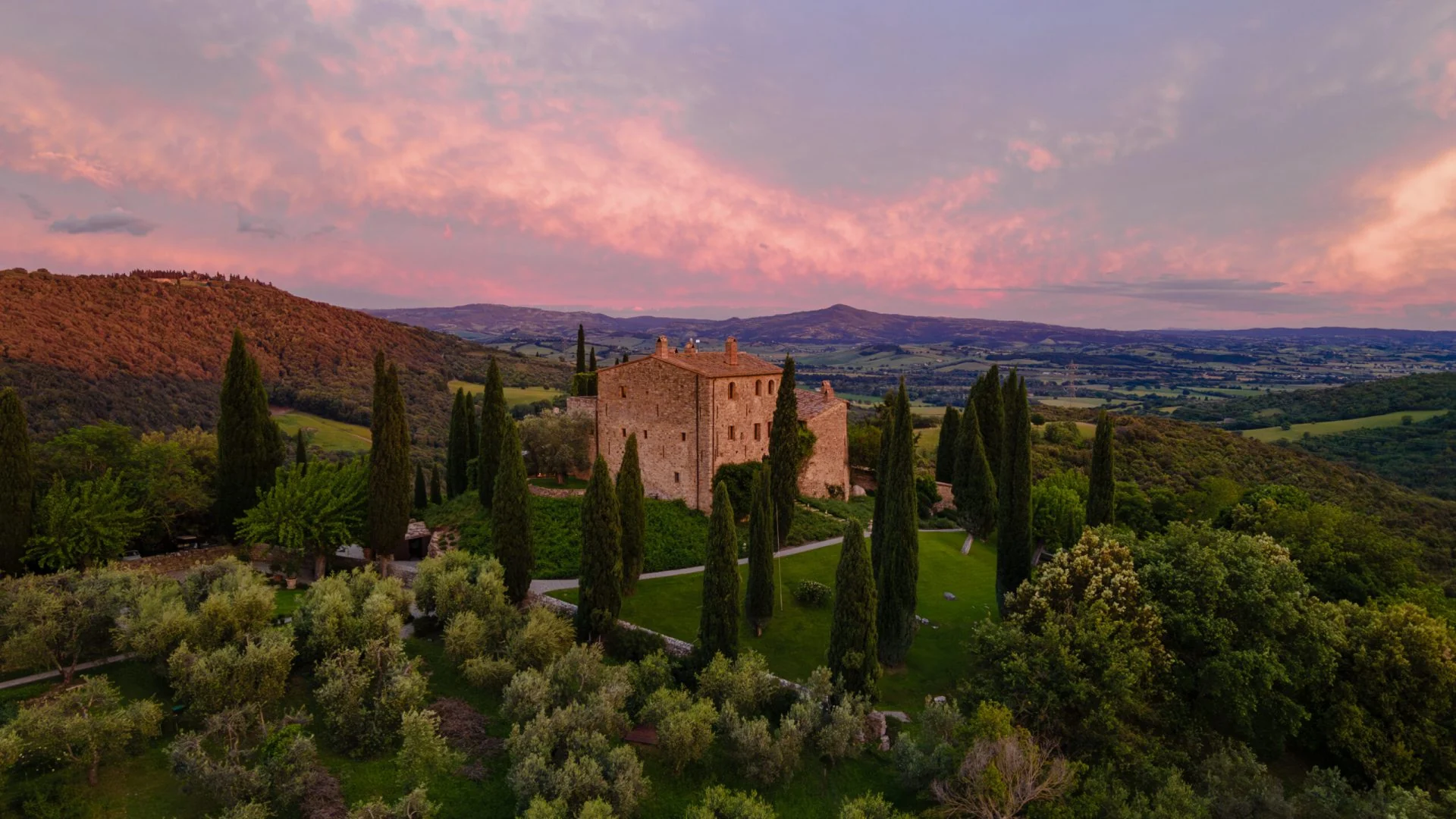 Castello di Vicarello in the Maremma: the stone castle, lawns and cypresses at dusk