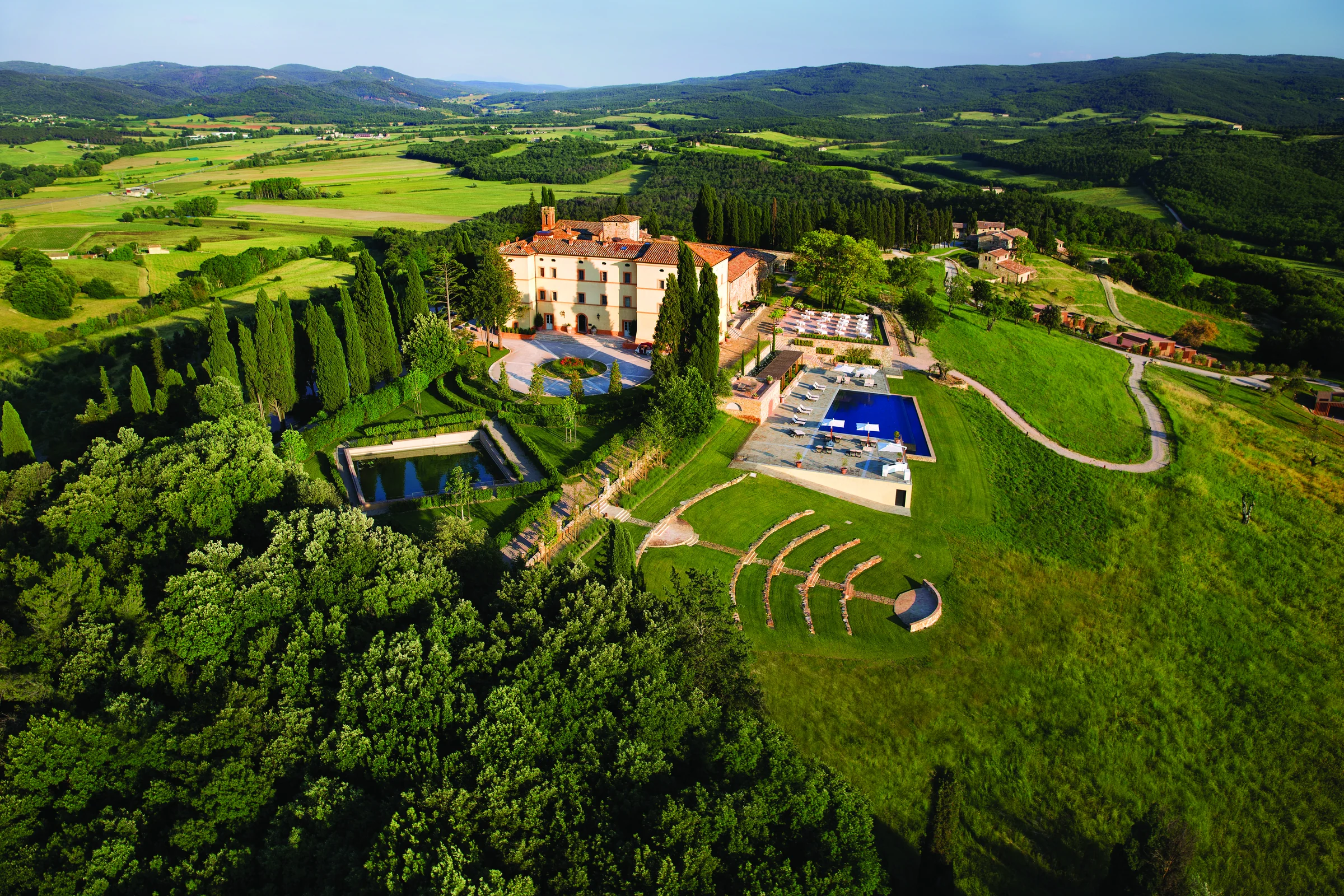 Castello di Casole estate in the Siena countryside: the castle, gardens, amphitheatre and pool seen from above